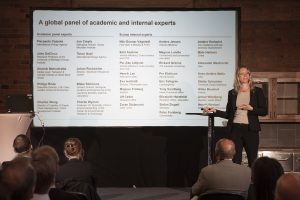 Female speaker on stage using PowerPoint presentation