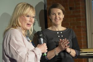 Two women, one of them speaking into microphone